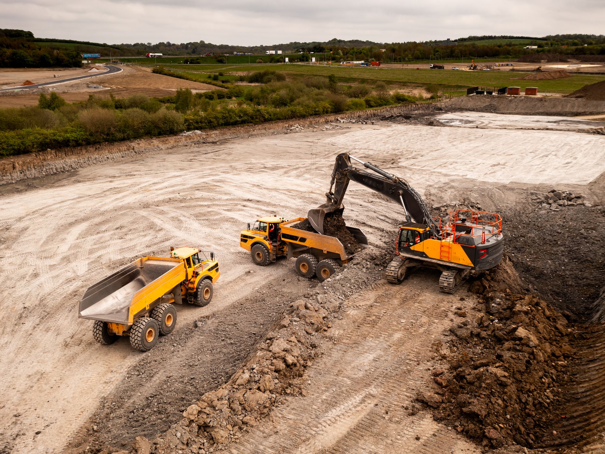 Excavator loading articulated dump trucks on a UK earthworks and quarry site
